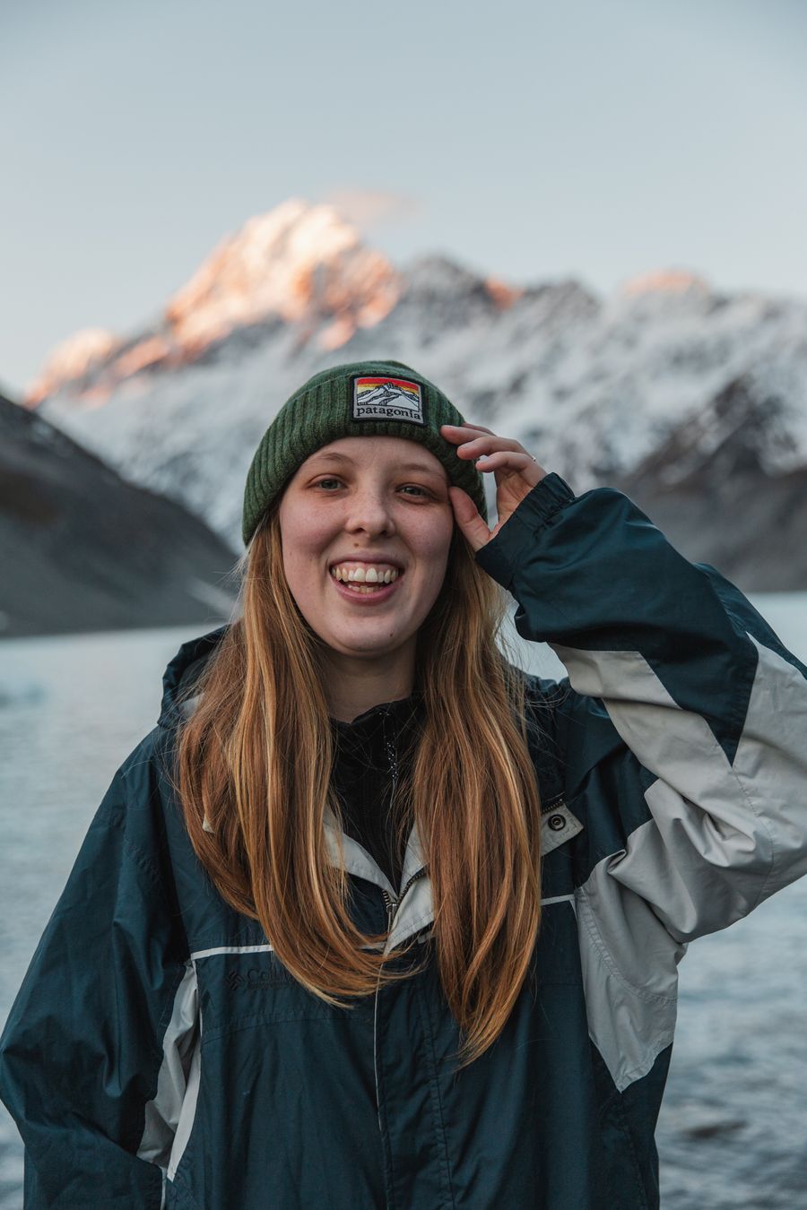 Abigail Hannah laughing in a beanie below Aoraki Mount Cook